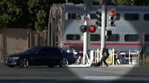 Cop reaches for man on tracks as train nears