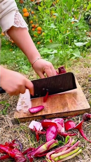 slicing the fresh red beets on a wooden board using a sharp serrated metal knife