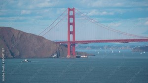 Wide shot showing end of Golden Gate Bridge hiding behind mountain in summer - Boats cruising on river bay in San Francisco