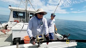 Spurge, aka "Father Tuna," gives some hands-on fishing lessons to his first mate, Ryan Fletcher, as they attempt to reel in a tuna. | National Geographic TV