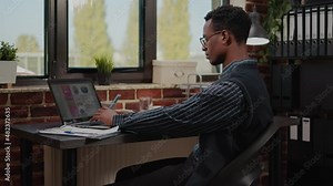 African american person working on e commerce statistics in company office. Business man using laptop to plan commercial report and financial investment for manager career development.